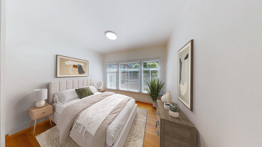 A bedroom with a large bed and a window with blinds.